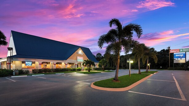 A TROP hotel with a large parking lot, palm trees, and a sunset sky. - Red Roof Inn Vero Beach - I-95 (Vero Beach)