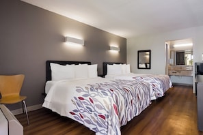A hotel room with a large bed, a chair, a desk, and a mirror. - Red Roof Inn Vero Beach - I-95 (Vero Beach)