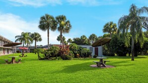 A well-maintained outdoor area with picnic tables and palm trees. - Red Roof Inn Vero Beach - I-95 (Vero Beach)