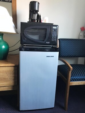 A small black microwave on top of a white mini-fridge with the brand 'BLACK & DECKER' visible. - Best Inn (Petersburg)