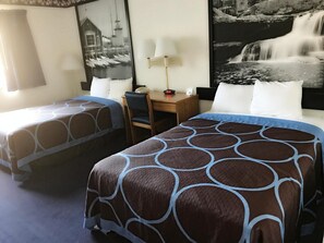 Quarto de hotel com duas camas, uma escrivaninha, uma cadeira e um painel mural grande.