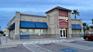 Un restaurant IHOP avec une façade en pierre, des auvents bleus et un parking comprenant des places réservées aux personnes handicapées.