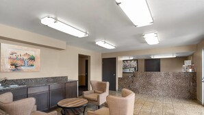 Un hall d’hôtel comprenant un coin cuisine, des sièges et des œuvres d’art accrochées aux murs.