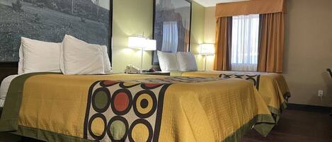 A hotel room with two beds, each with a patterned bedspread, a nightstand, a lamp, and a large framed picture on the wall.