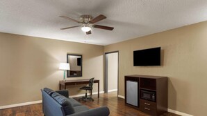 Une chambre d’hôtel équipée d’un ventilateur de plafond, d’un téléviseur à écran plat, d’une kitchenette, d’un canapé, d’un bureau et d’une chaise.