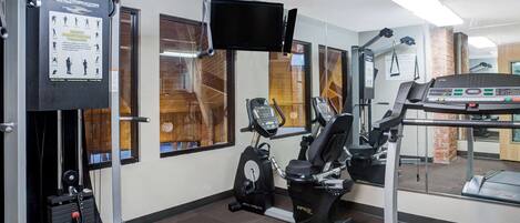 A gym with exercise equipment, a treadmill, and a wall-mounted TV.