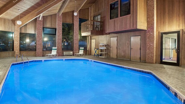En inomhuspool med väggar av trä och en balkong med utsikt över poolen.