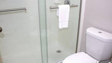 Un baño con ducha acristalada, un inodoro blanco y un perchero para toallas.