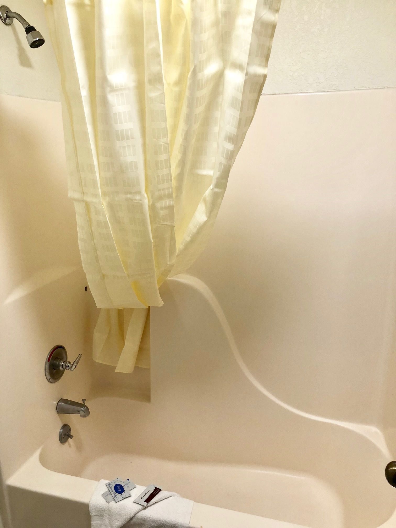 A bathtub with a showerhead, a towel, and a bottle of shampoo.