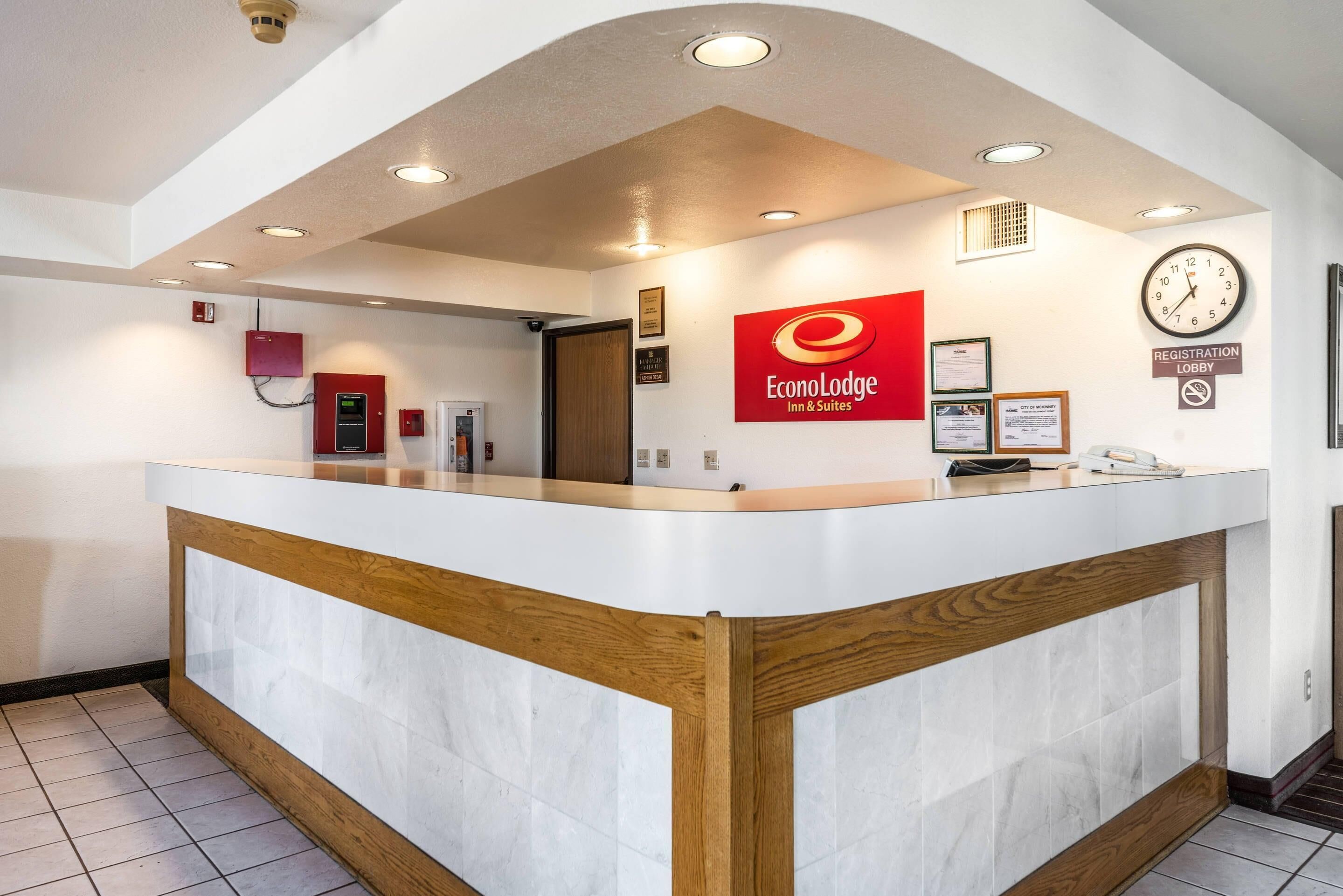 A reception desk with a clock, a sign for the registration lobby, and a fire extinguisher.
