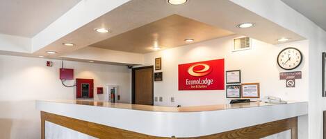 A reception desk with a clock, a sign for the registration lobby, and a fire extinguisher.
