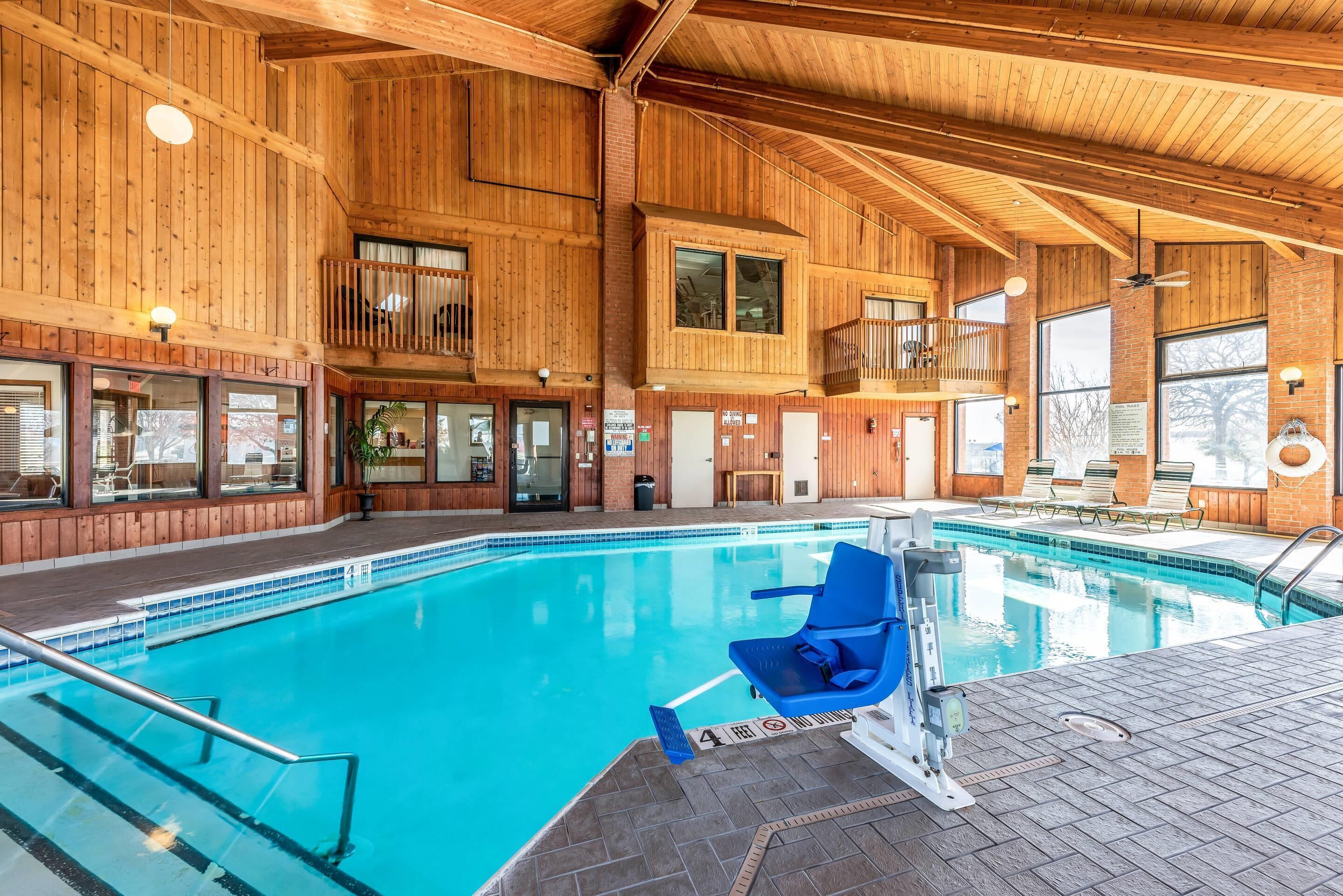 A large indoor swimming pool with wooden walls and a balcony overlooking the pool.