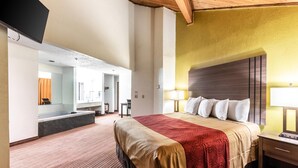 A hotel room with a large bed, a desk, a mirror, and a bathroom visible through an open door. - Econo Lodge Inn & Suites Mckinney - Plano North (McKinney)