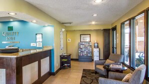 A reception area with a blue wall, a reception desk, a water cooler, and seating with a view of the outside. - Quality Inn Murray University Area (Murray)