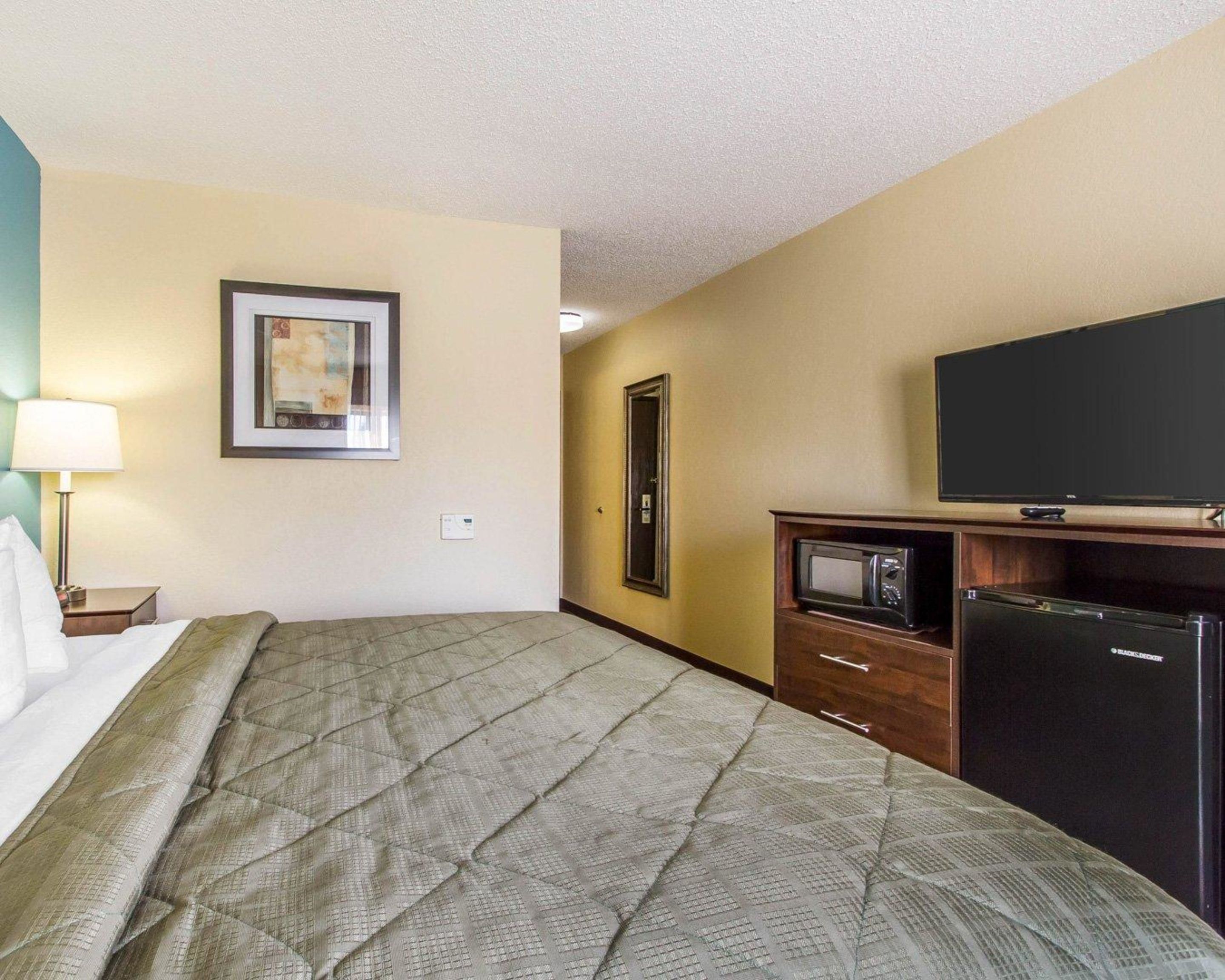 Una habitación de hotel con cama, televisión, microondas y cómoda.