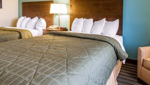 A hotel room with two beds, a nightstand with a lamp, and a wooden headboard. - Quality Inn Murray University Area (Murray)