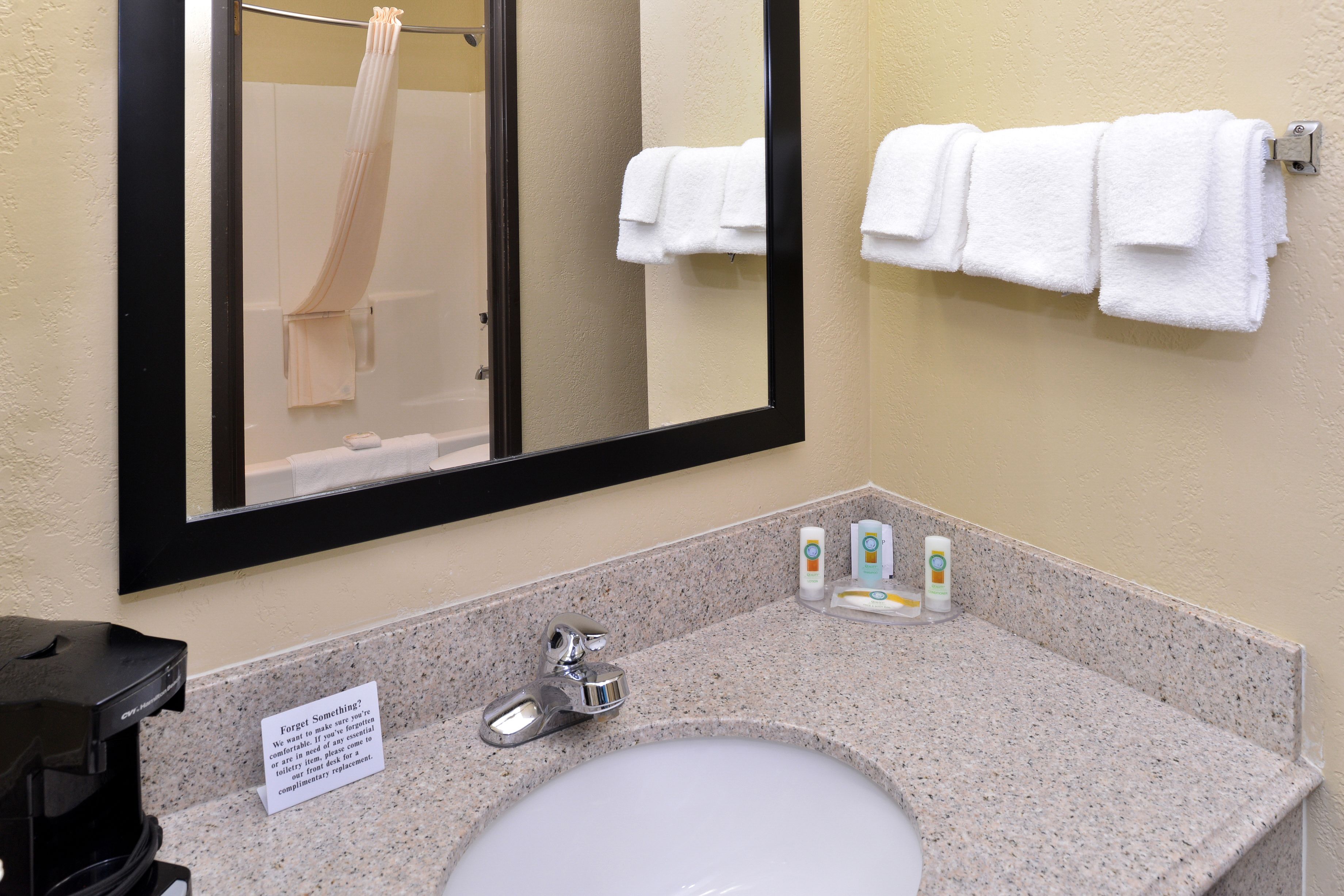 Un bagno con lavandino, specchio, portasciuga e articoli da toilette.