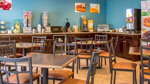 A restaurant with a blue wall, various food and drink dispensers, and seating for diners.