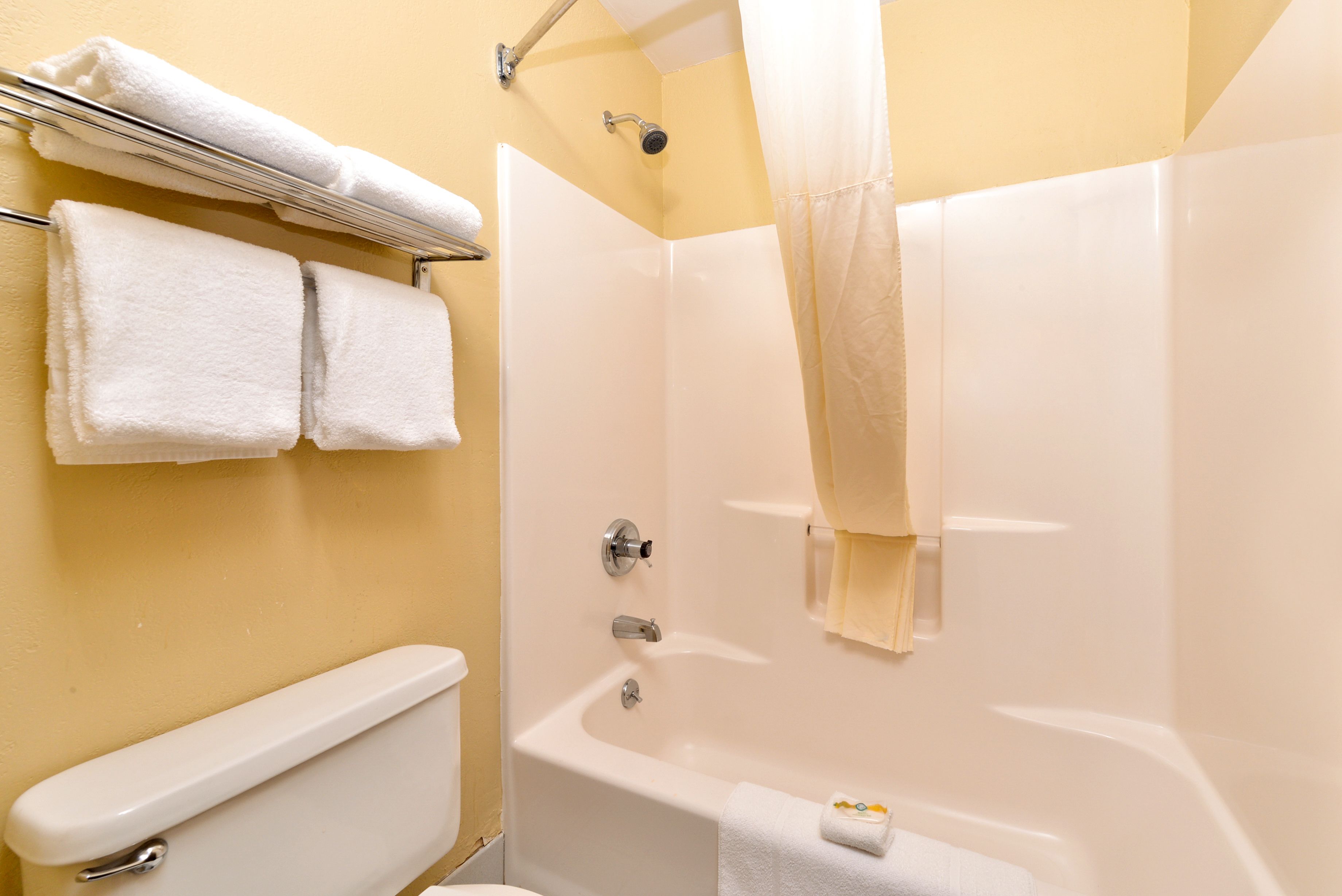 Un baño con una bañera blanca, un inodoro y un perchero con dos toallas.