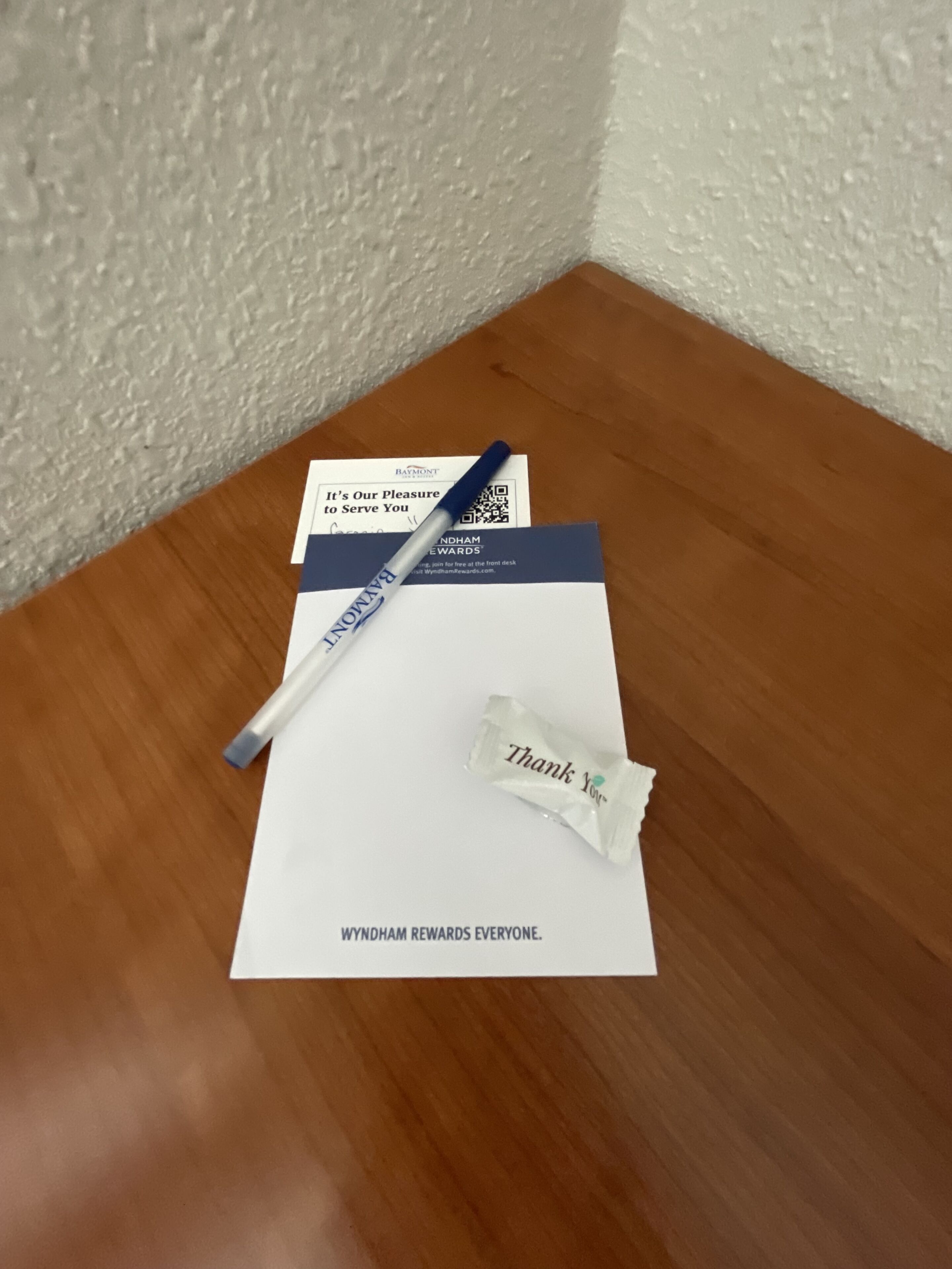 A thank you note, a pen, and a brochure on a wooden table.