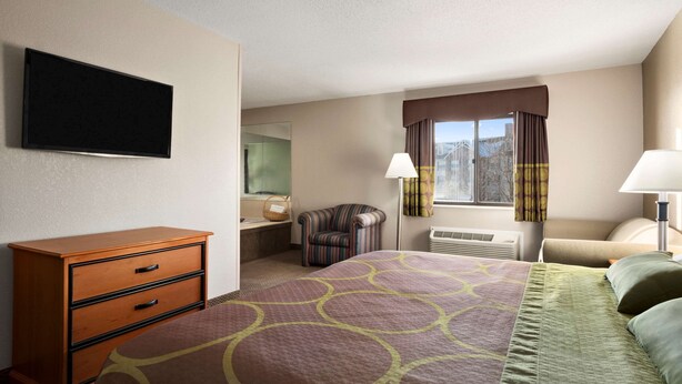 A hotel room with a bed, a dresser, a chair, a TV, a window with curtains, and a lamp. - Super 8 by Wyndham Green Bay I-43 Bus. Park (Green Bay)