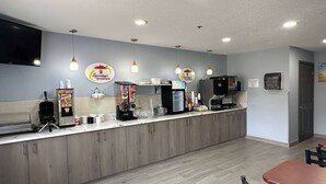 A breakfast bar with a coffee machine, a TV, and a sign for 'Sopostart breakfast'.