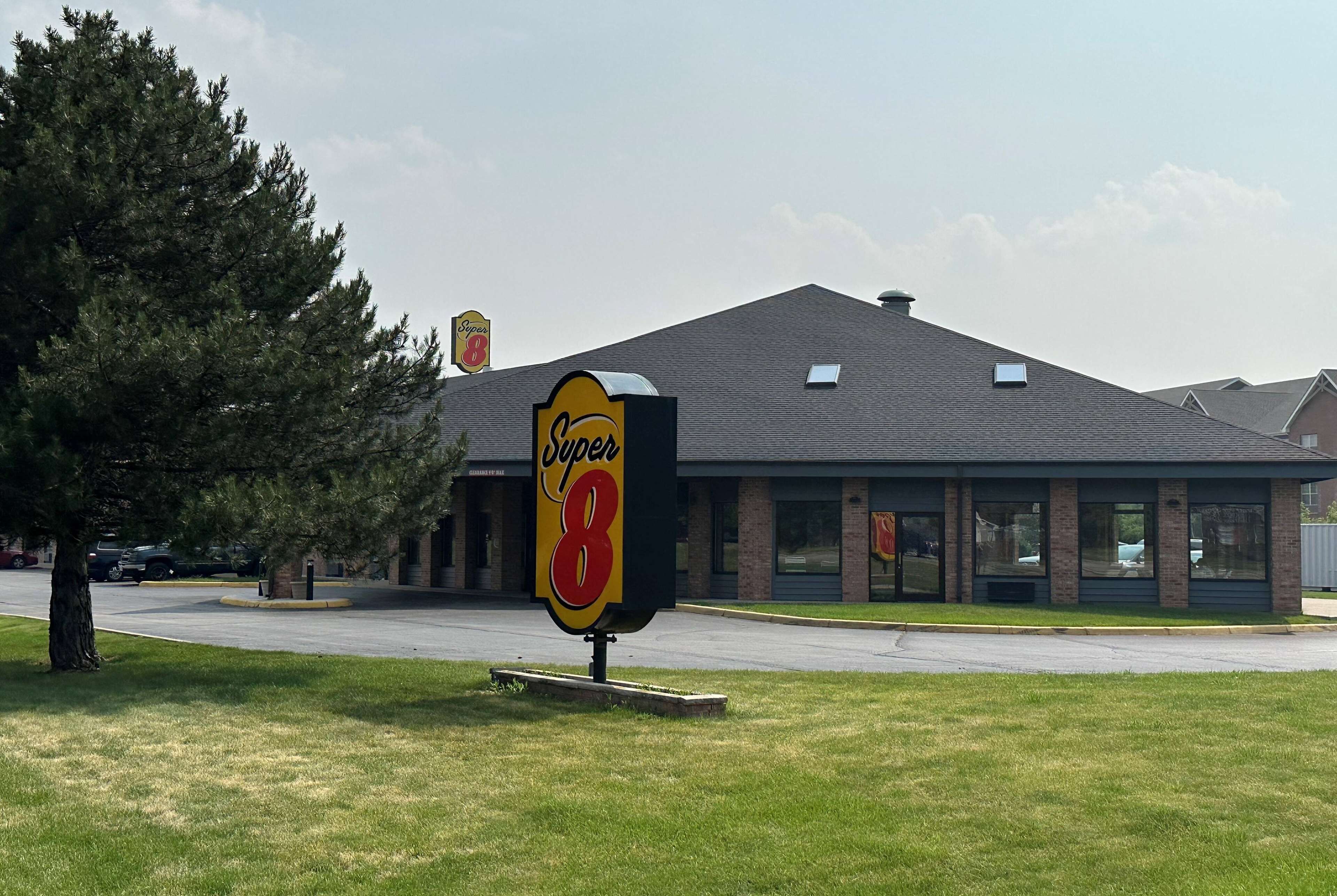 Un motel de type Super 8, avec une grande enseigne, une façade en briques et un parking.
