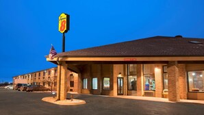 A Super 8 motel with a parking lot, American flags, and a clear sky.