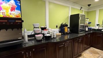 Una cocina con cafetera, refrigerador y un amplio ventanal.