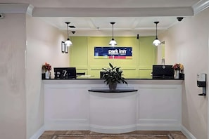 Welcome to Park Inn, where guests can check in at the central reception desk, surrounded by a potted plant and a digital sign displaying the hotel's name.
