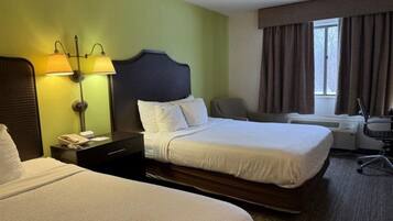 A hotel room with a large bed, two bedside lamps, a desk with a chair, and a window with curtains.