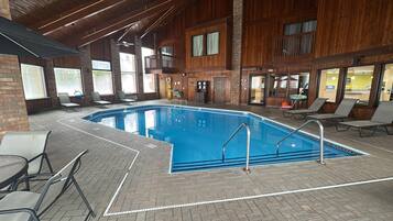 Una piscina interna con pavimento in mattoni e lettini intorno.