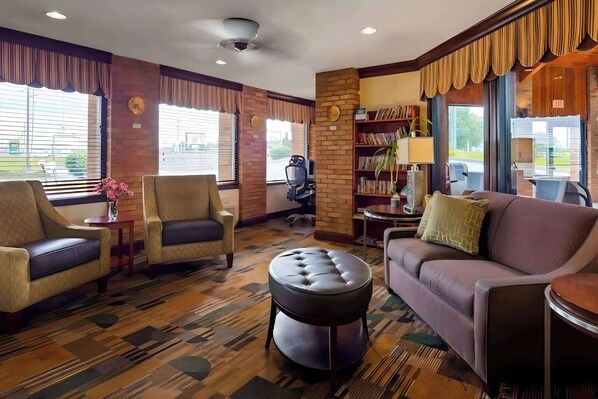 Relax in the hotel lobby's comfortable seating area, featuring armchairs, a sofa, and a round ottoman.