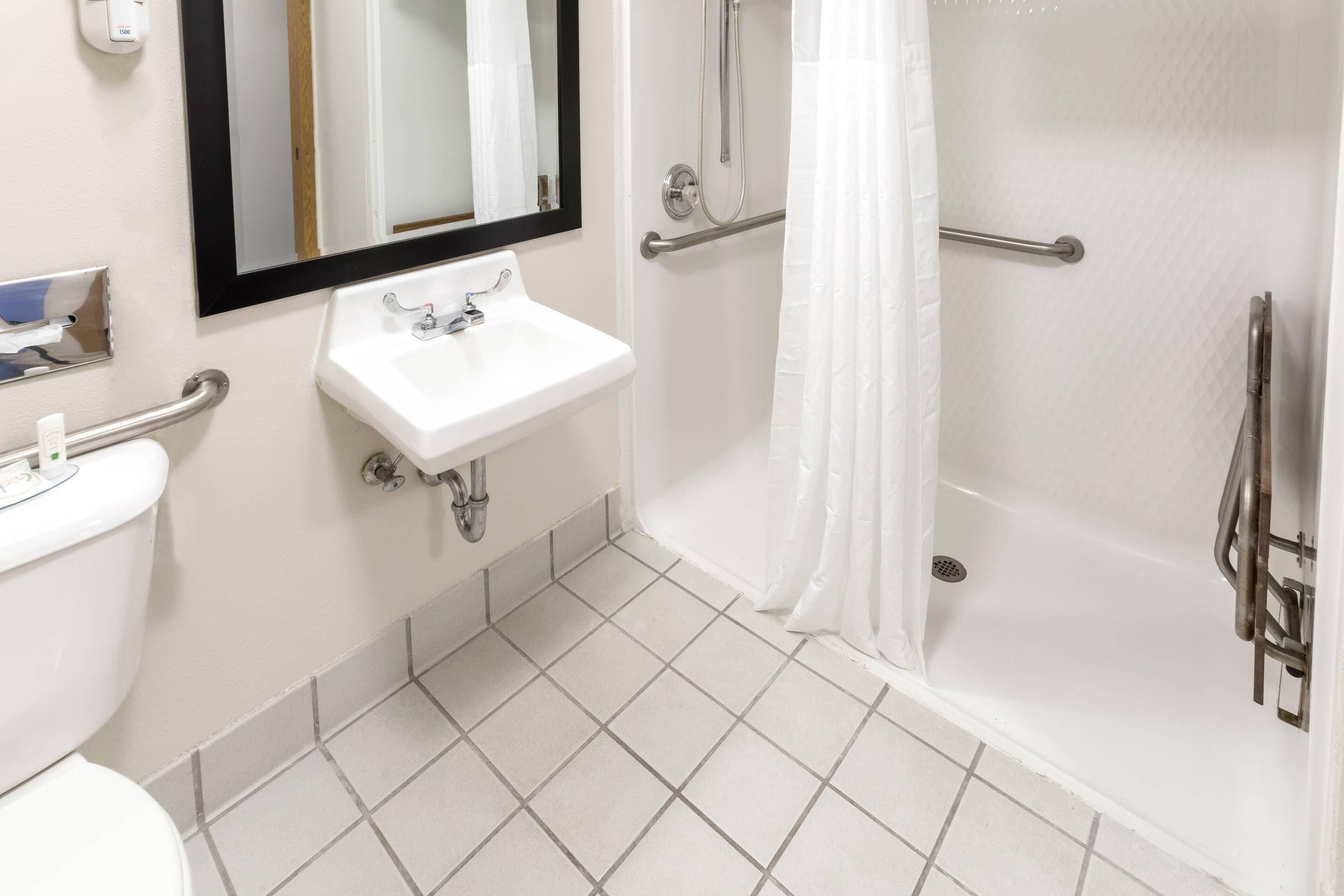 A bathroom with a white sink, mirror, and shower area.