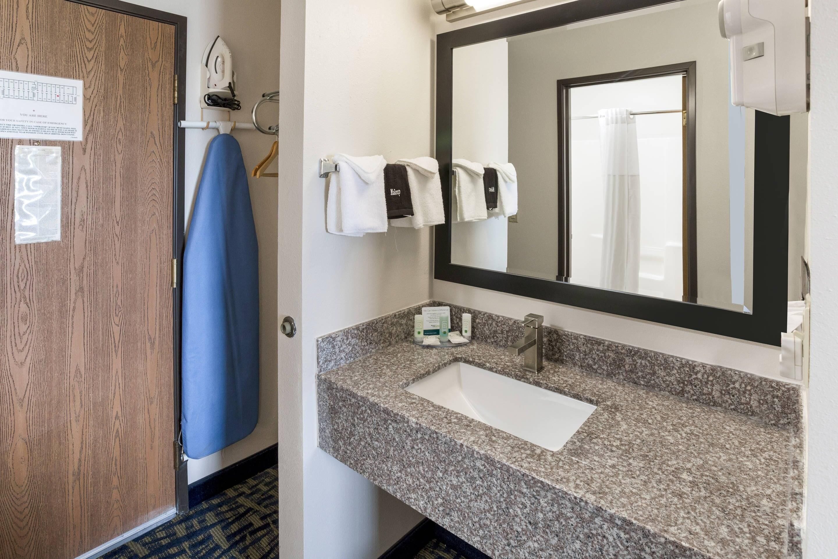 A bathroom with a granite countertop sink, a mirror, a towel rack with towels, and a blue towel hanging.