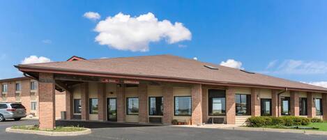A two-story motel with a brick facade, large windows, and a covered parking area.