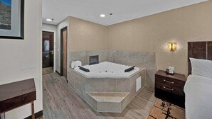 Un bagno moderno con una vasca da bagno freestanding, un comodino in legno con una sveglia e un quadro appeso al muro.