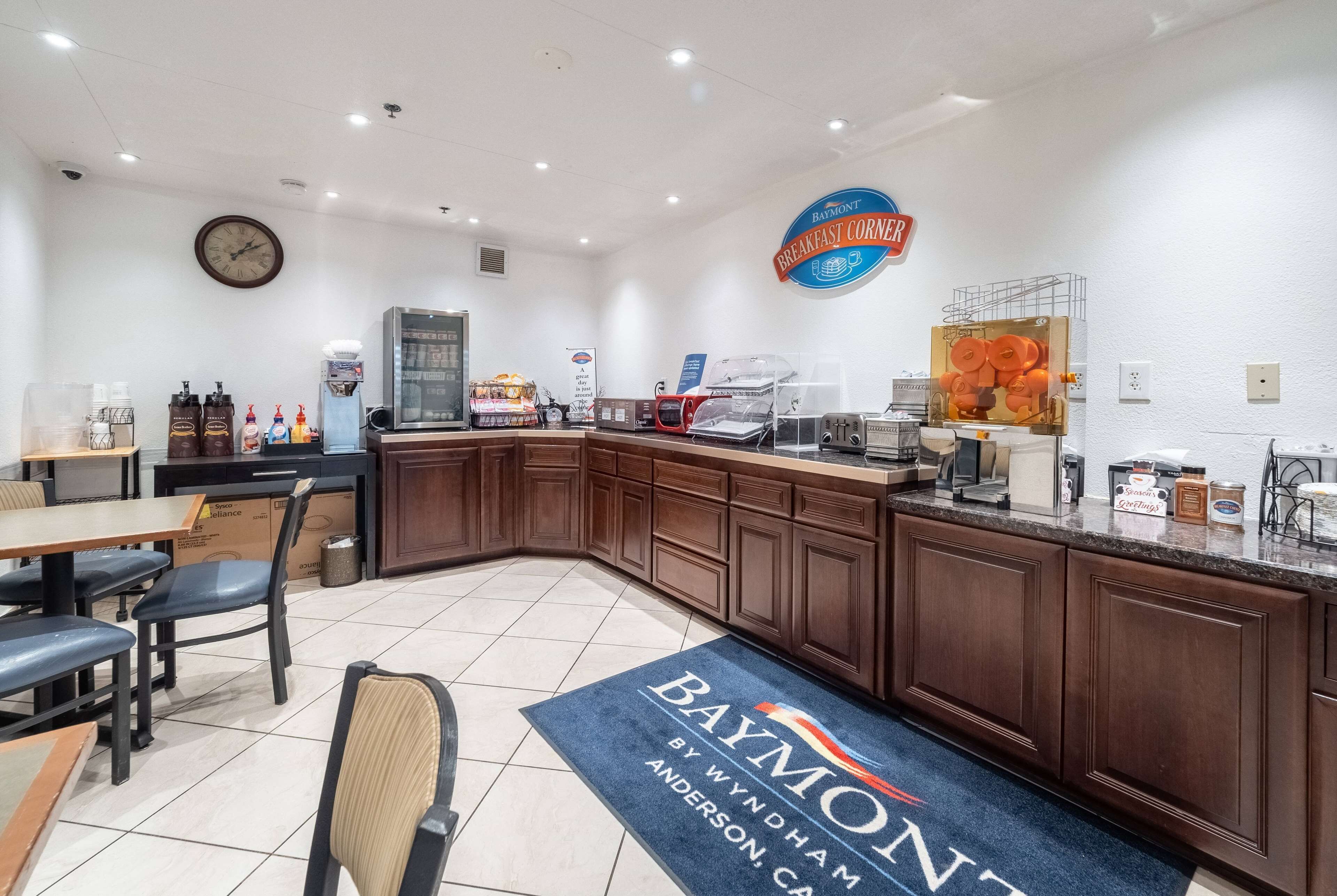 A breakfast area with a Baymont sign, a clock, a coffee machine, and a menu board.