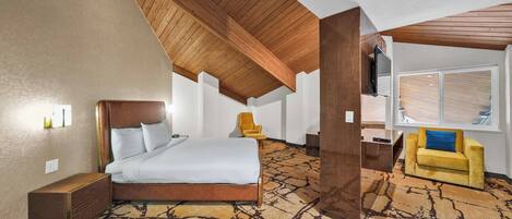 Une chambre d’hôtel avec un grand lit, un canapé, une télévision et une fenêtre avec des stores.
