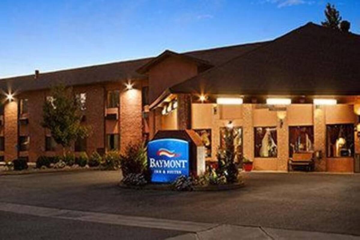 A hotel with a prominent sign, a parking lot, and a building facade.