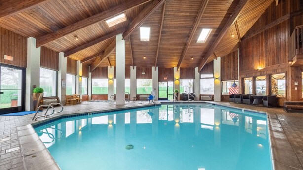 Una piscina interna con travi in legno e ampie finestre.