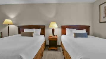 Habitación de hotel con dos camas, cada una con cabecera de madera, una mesita de noche con lámpara y un cuadro enmarcado en la pared.