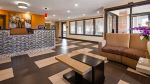 A lobby with a reception desk, a sofa, a coffee table, and a large window with blinds. - Best Western Jacksonville Inn (Jacksonville)