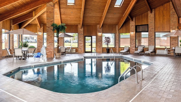 An indoor swimming pool with a wooden ceiling, brick walls, and a view of the outside. - Best Western Jacksonville Inn (Jacksonville)