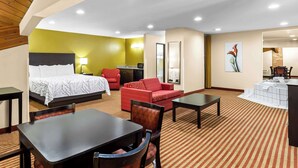 A hotel room with a bed, a red sofa, a dining table, and a small kitchenette. - Best Western Jacksonville Inn (Jacksonville)
