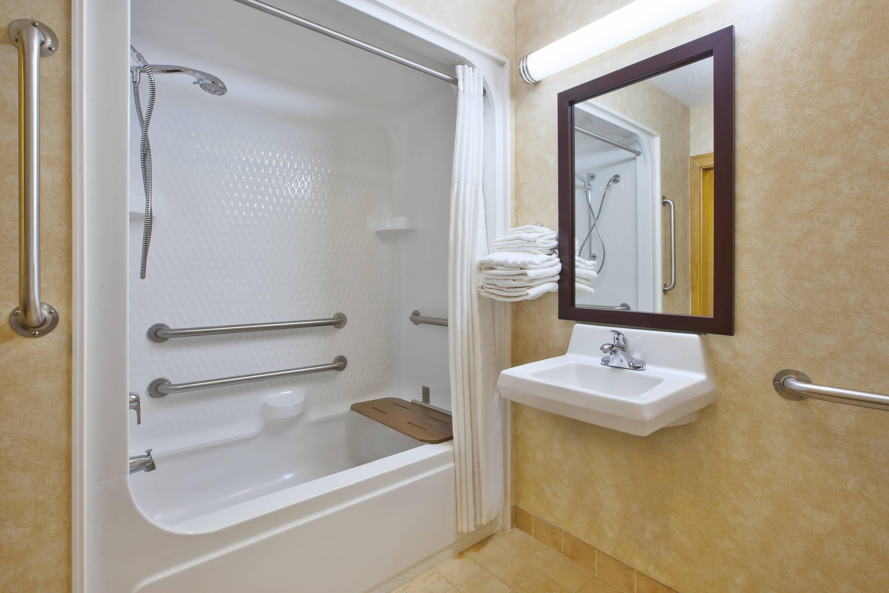 A bathroom with a bathtub, a sink, and a mirror.