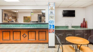 Interior de un restaurante con mostrador, paneles de madera, un televisor en la pared y una columna decorada con pegatinas.