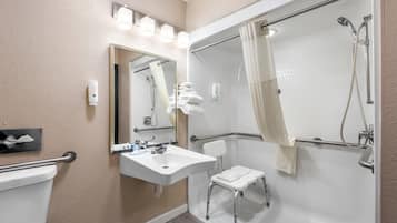 A bathroom with a toilet, sink, mirror, shower, and a small step stool.