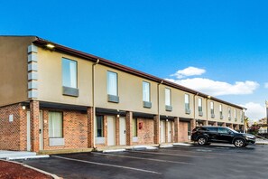 Une rangée de maisons de ville en briques, avec un parking devant.