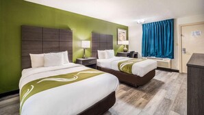 A hotel room with two beds, a green wall, and a blue curtain. - Quality Inn Columbia Airport (West Columbia)